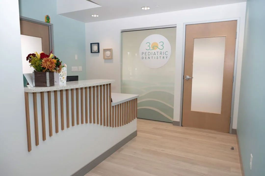 The image shows an interior view of a dental office reception area with a modern design, featuring a desk, counter, and a glass door with a sign that reads  360 Dental.